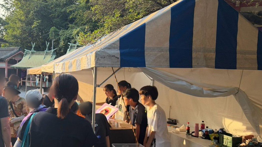 青と白の天幕の下で、並んだお客さんに応対する子どもたち
